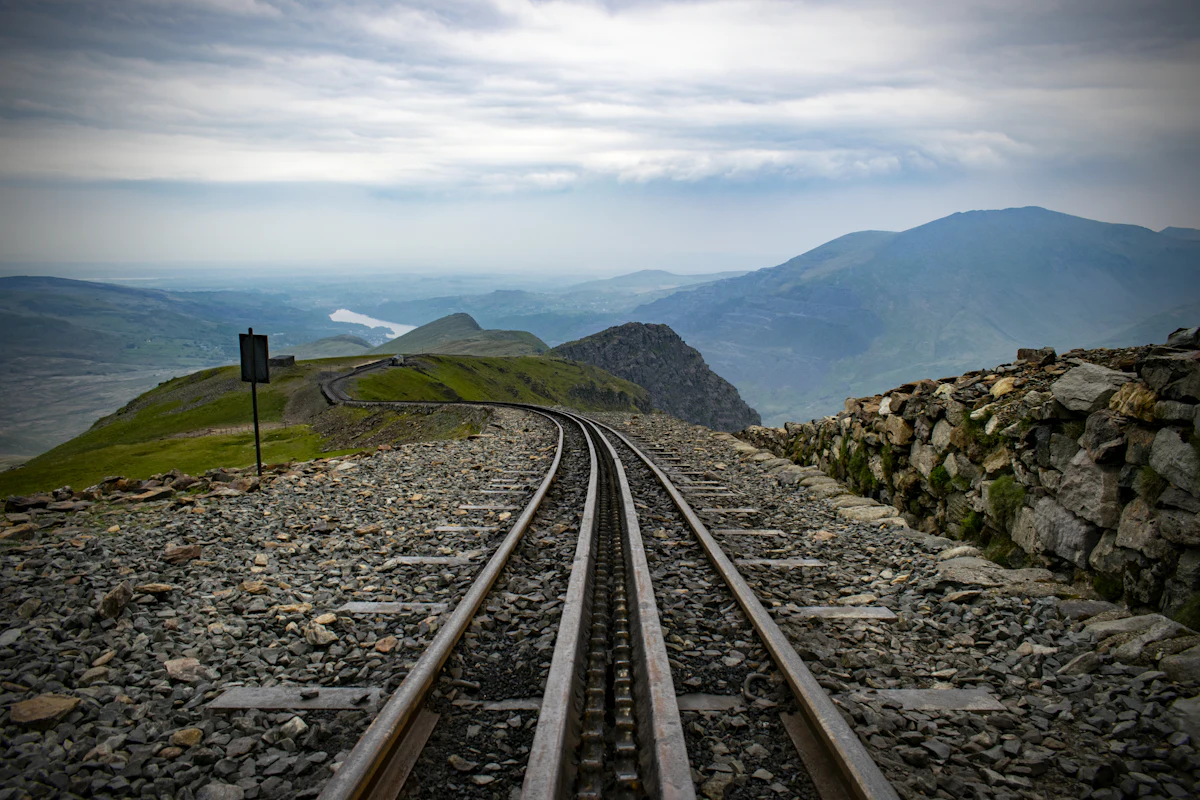 The Snowdon Mountain Railway track running down a stony ridge, with hills and a lake far below