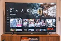 A television screen displaying the Netflix interface is shown. The main focus is the show 'Dark' with a large image from the series. Below it are recommendations for 'Continue Watching,' including shows like 'Selling Sunset,' 'Friends,' and 'Community.' The interface includes the Netflix logo and an array of show thumbnails.