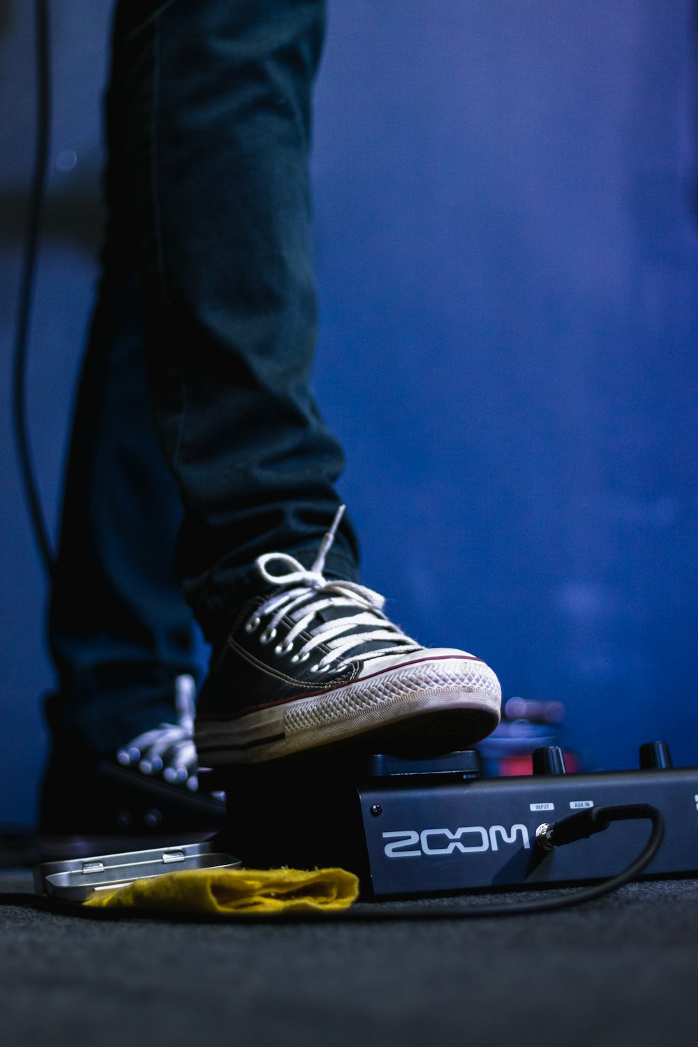 person in blue denim jeans and black and white adidas sneakers standing on black guitar amplifier