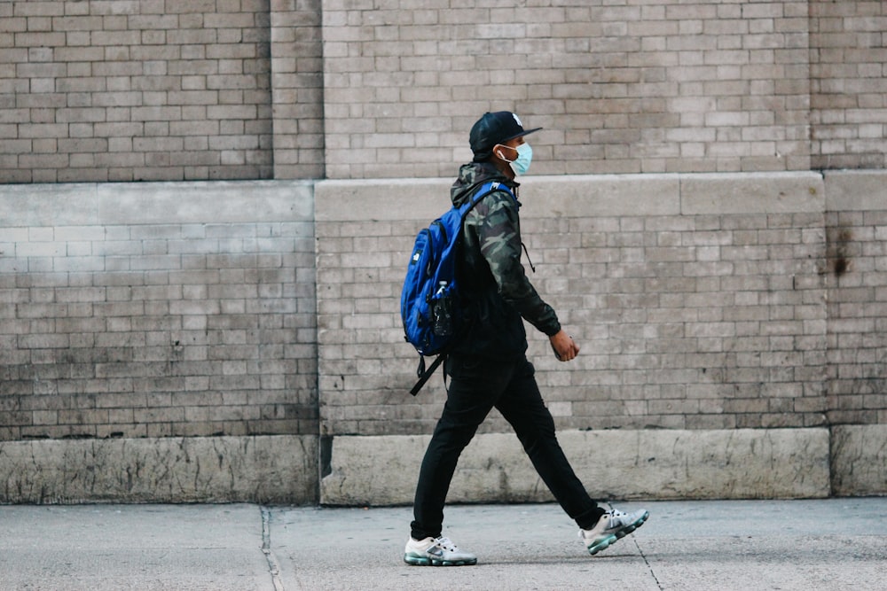 man in black jacket and black pants walking on sidewalk during daytime