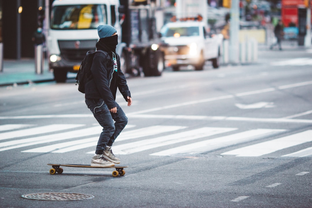man in black jacket and blue denim jeans riding yellow skateboard during daytime