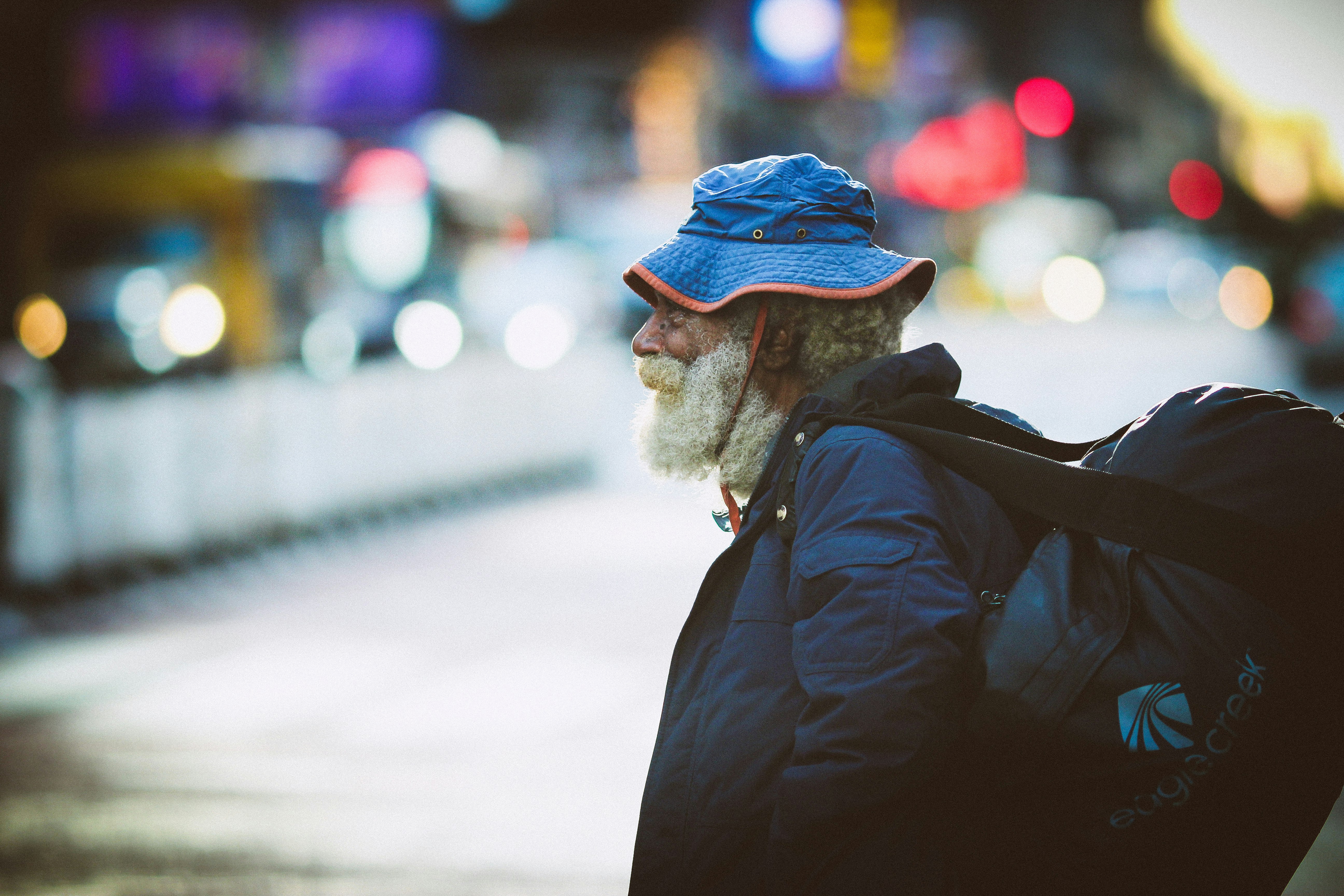 man in black jacket and blue knit cap standing on road during daytime