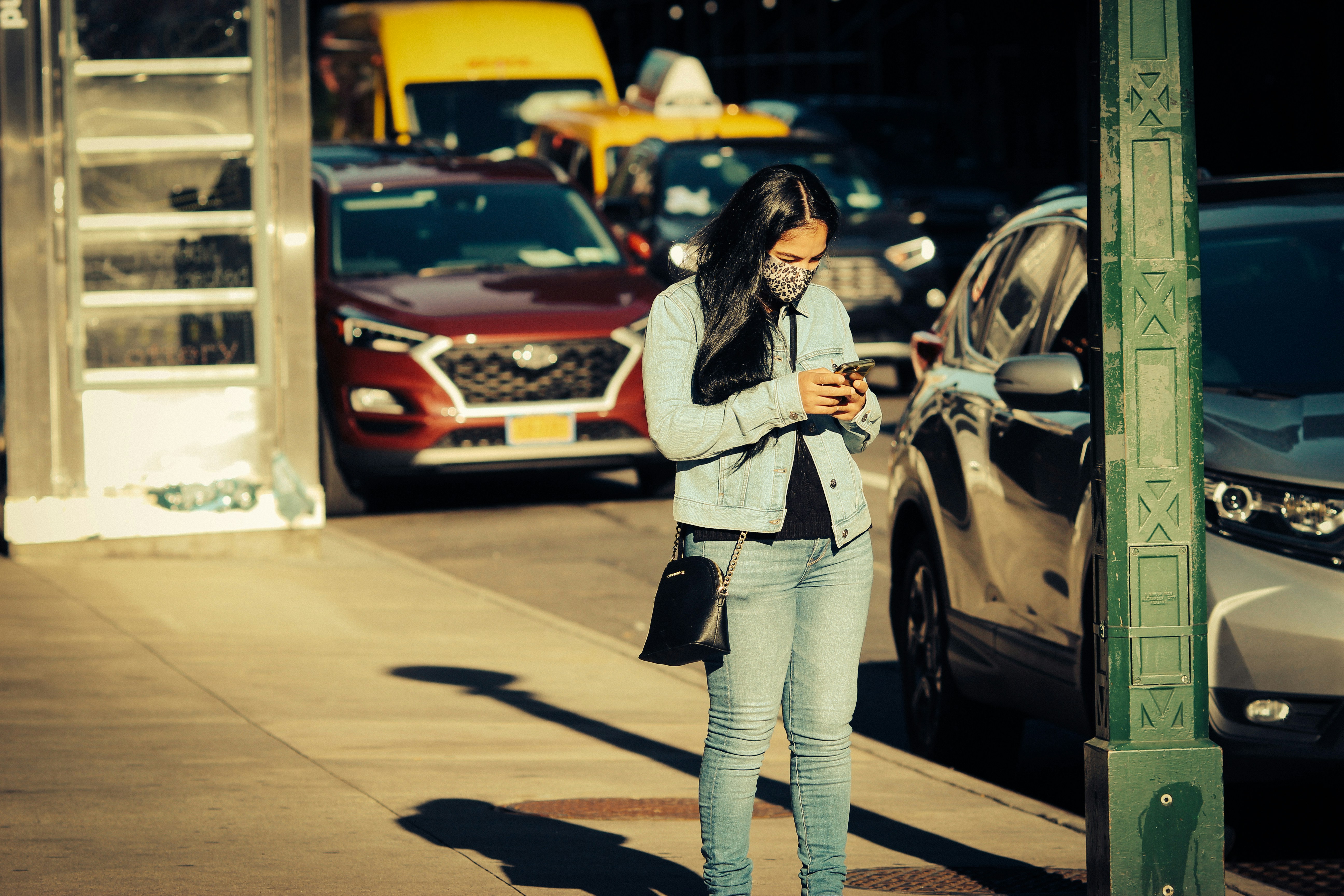 A woman checking her phone, possibly sharing live location, before getting into a taxi.