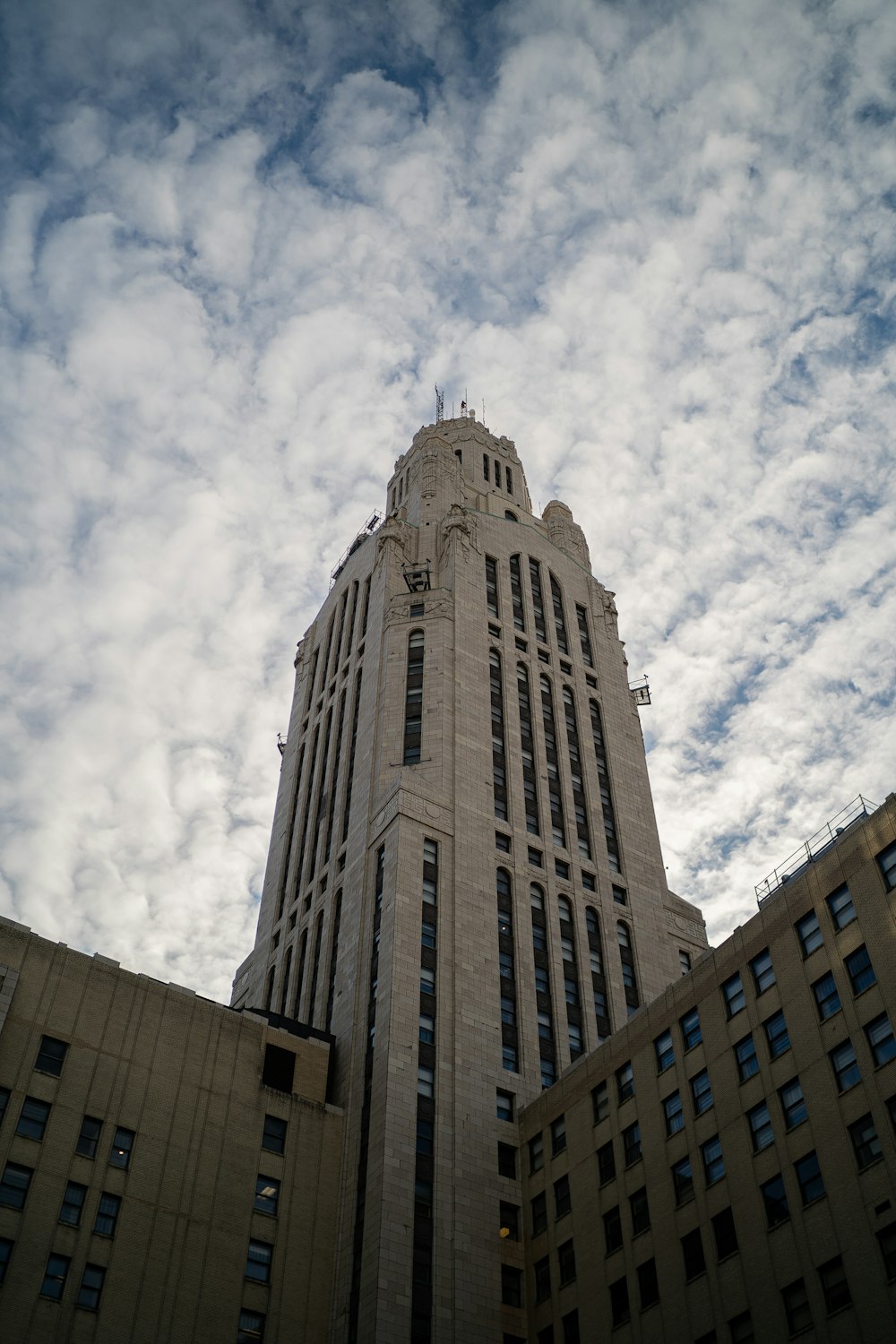 Fotografía de bajo ángulo de un edificio de hormigón gris bajo nubes blancas durante el día