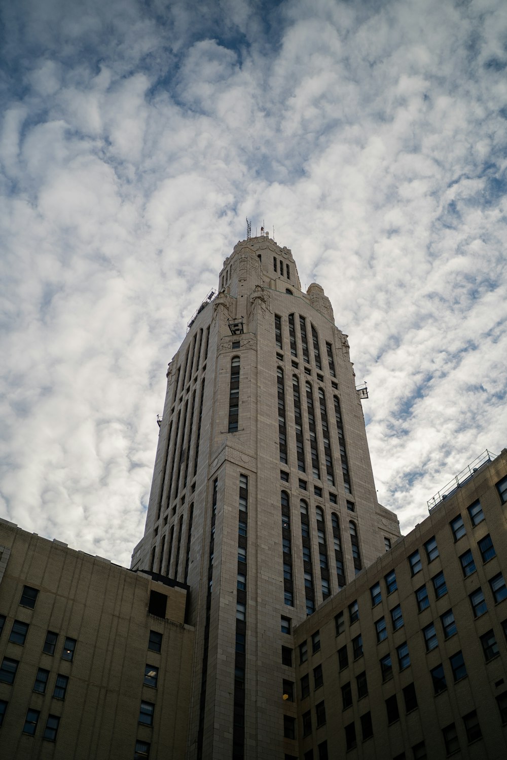 low angle photography of gray concrete building under white clouds during daytime