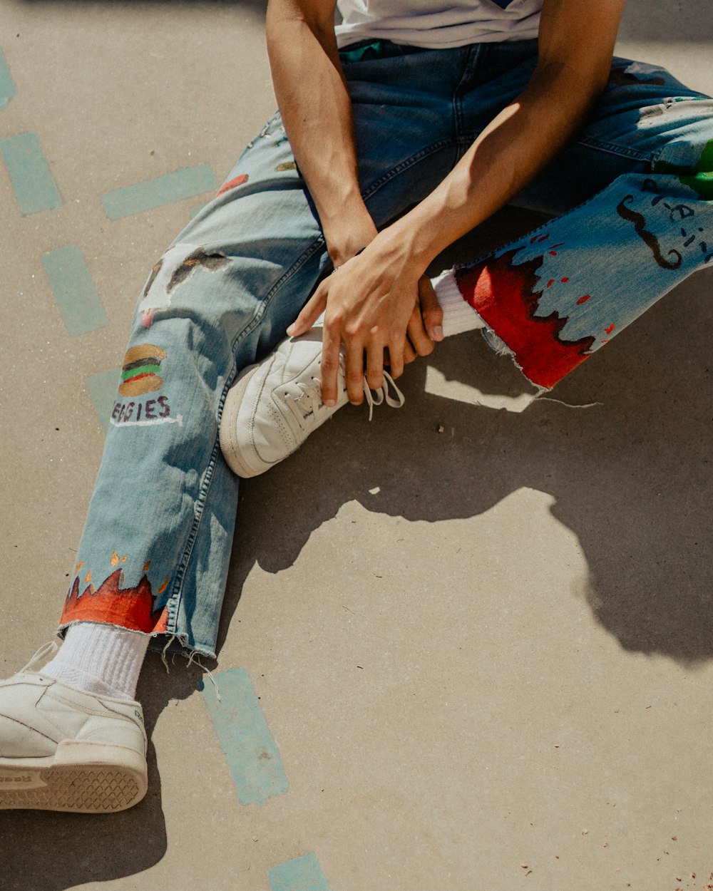 man in blue t-shirt and blue denim jeans sitting on red and blue skateboard