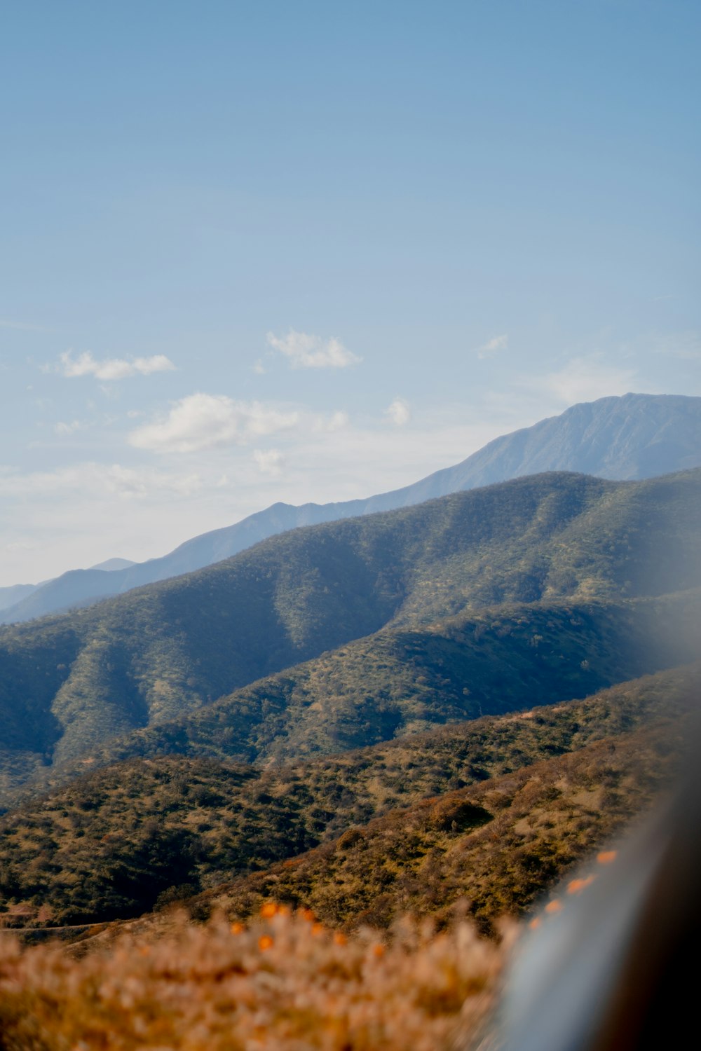 brown and green mountains under white clouds and blue sky during daytime