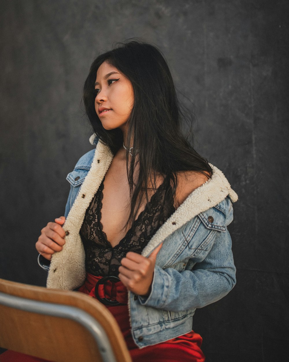 woman in blue denim jacket sitting on brown wooden chair