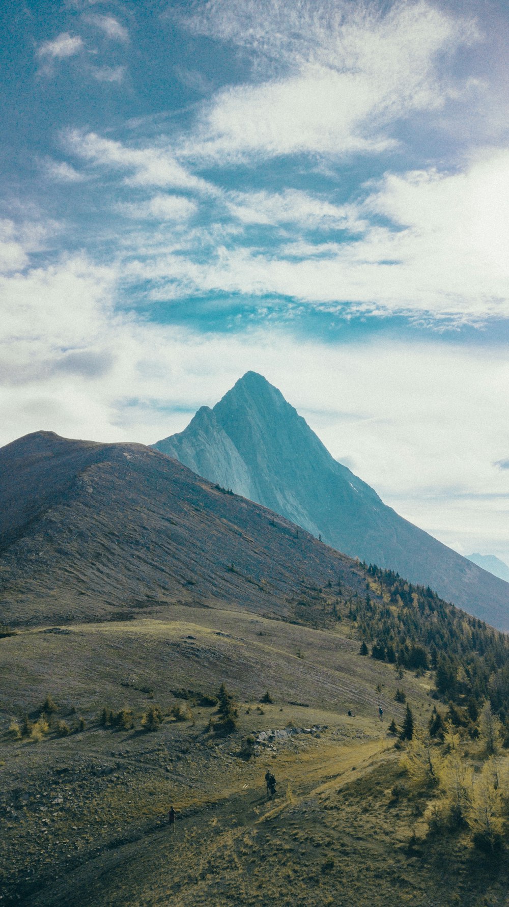 green and brown mountains under white clouds and blue sky during daytime