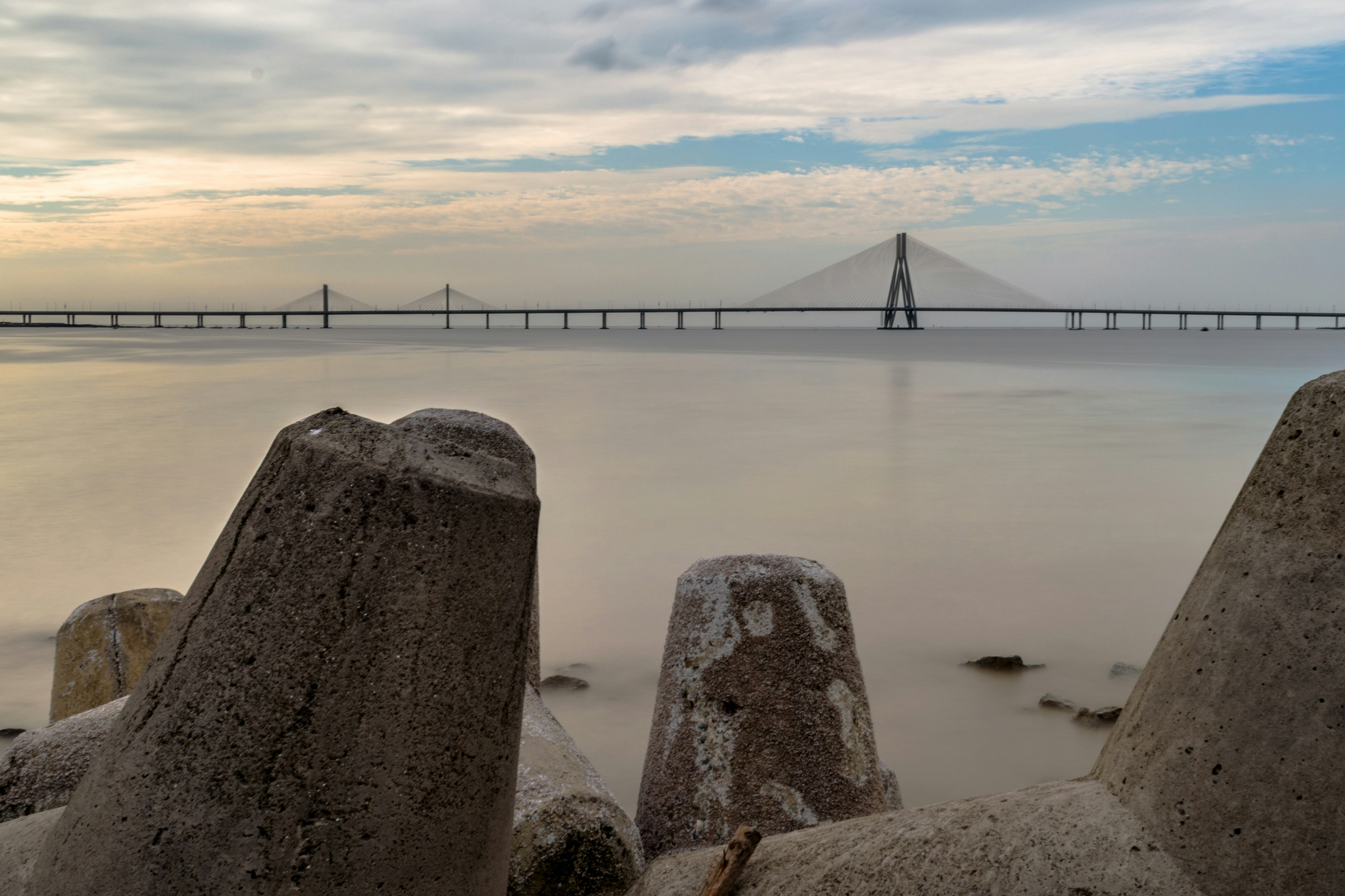 gray rock formation near bridge under white clouds during daytime