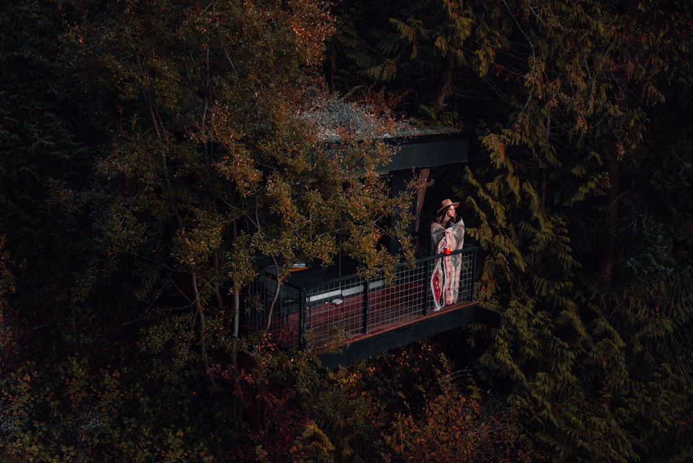 茶色の木製の橋の上に立つ赤と白の格子縞のドレスシャツを着た女性