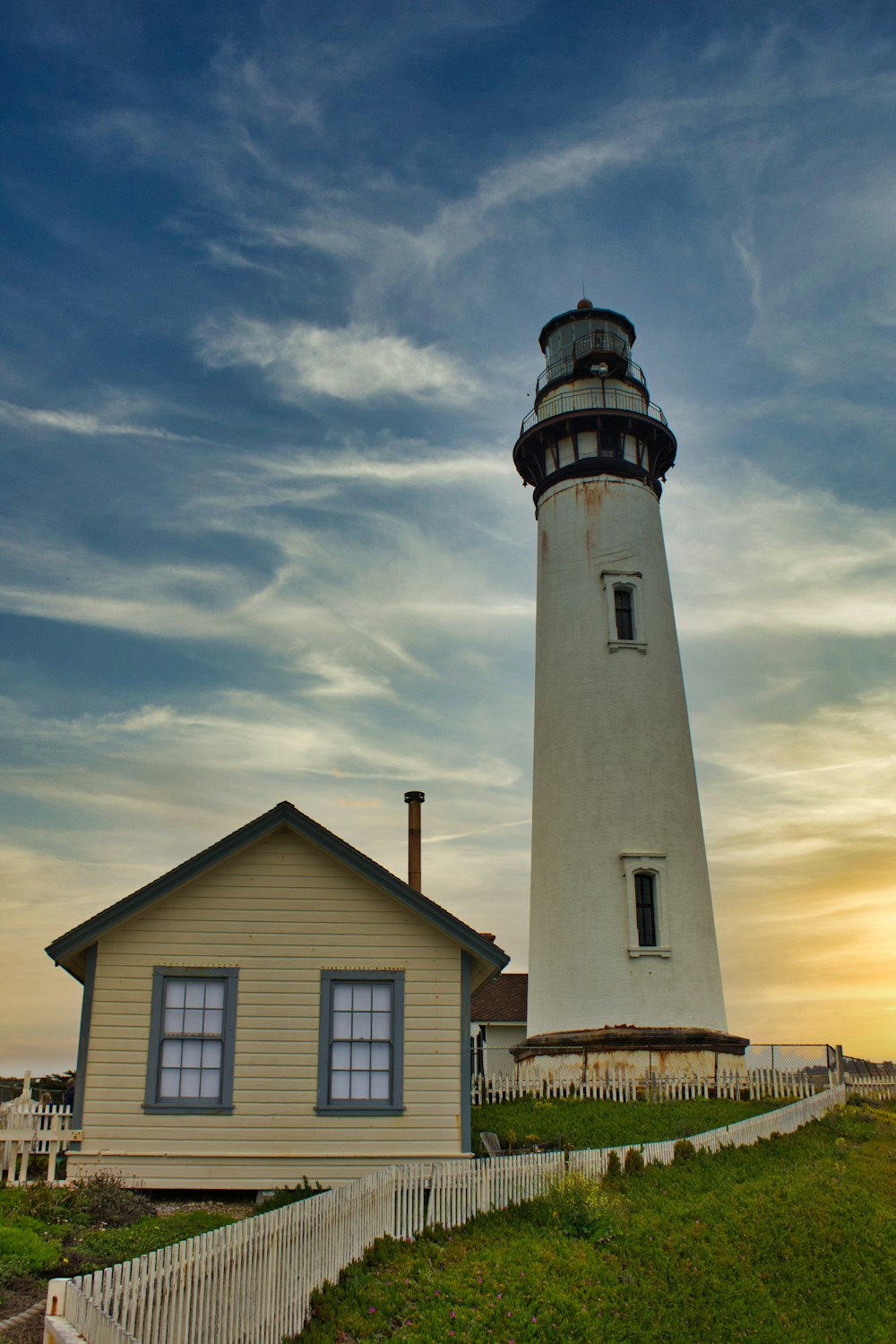 white and black lighthouse under cloudy sky during daytime