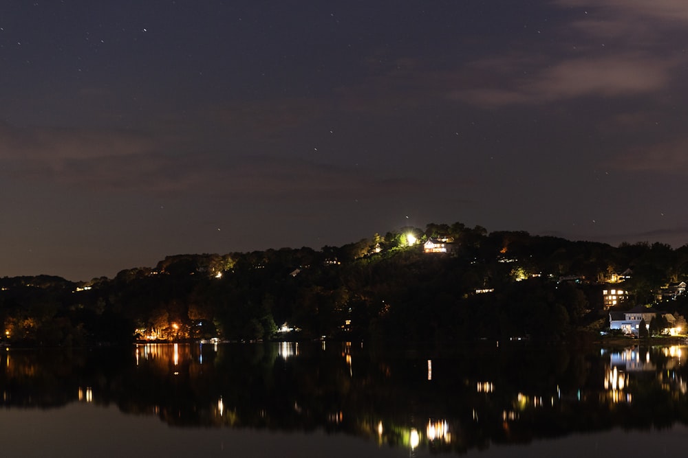 body of water near green trees during night time