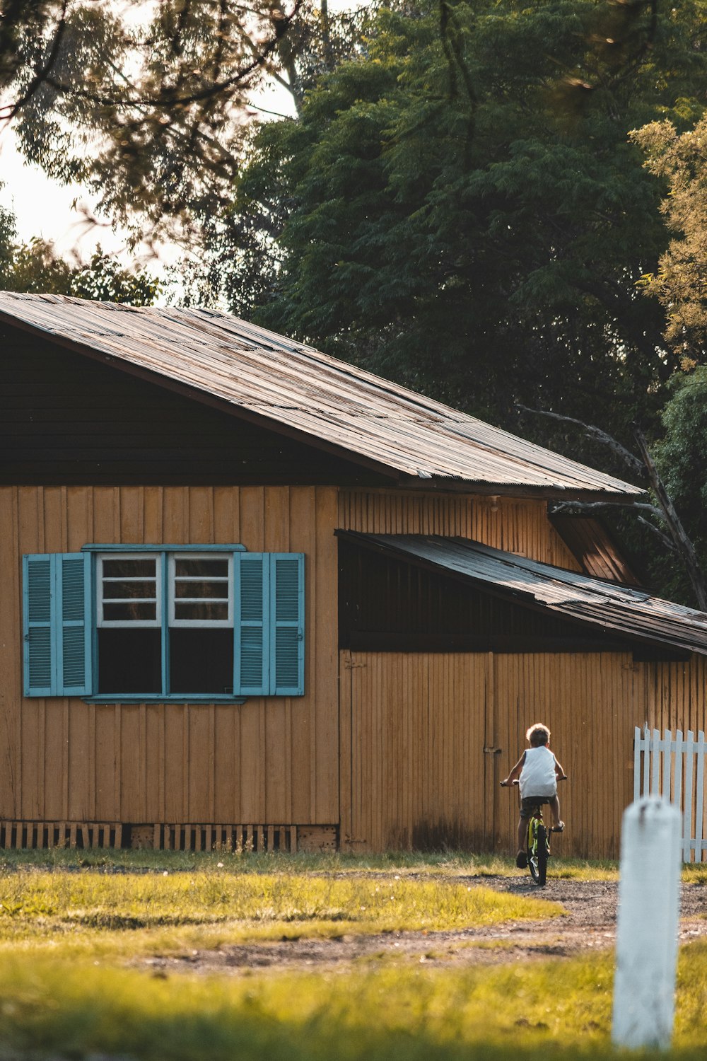 man in white shirt standing near brown wooden house