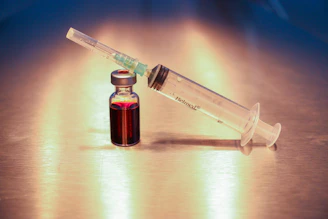 Close-up of a vial filled with clear peptide solution resting on a sleek white surface.