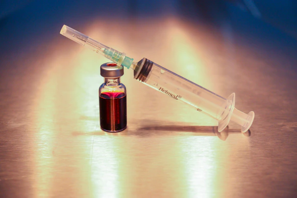 Close-up of a vial filled with clear peptide solution resting on a sleek white surface.