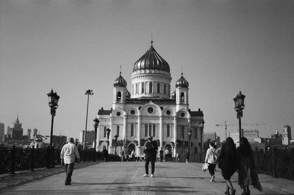 grayscale photo of people walking on street near building