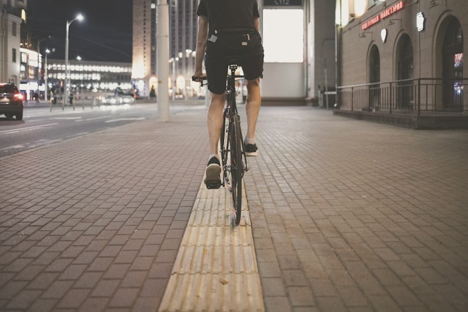 Person riding a bicycle on a sidewalk, the kind of route families will use for the event