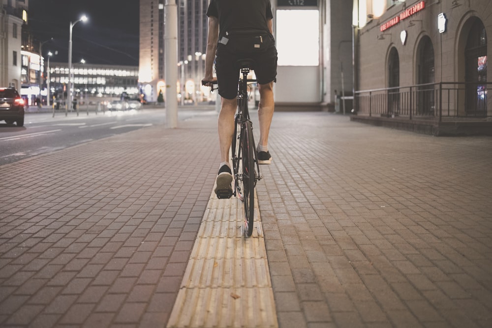 person in black jacket riding bicycle on sidewalk during daytime