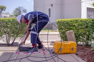 man in gray shirt and black pants holding black hose