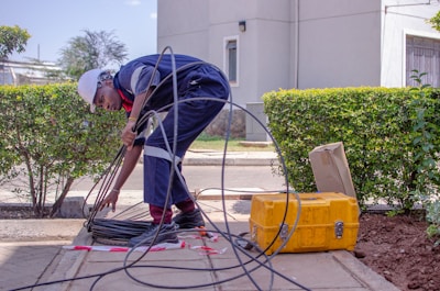 man in gray shirt and black pants holding black hose