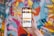 A hand holding a smartphone displaying a user interface for a food delivery app with options for dishes, collections, menus, and places near the user. The background showcases a vibrant and colorful graffiti mural with abstract and humanoid shapes.