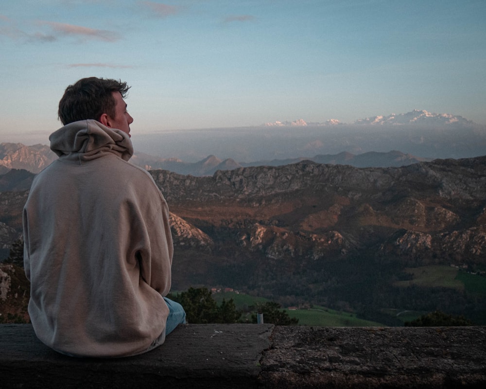 a man sitting on top of a wooden bench