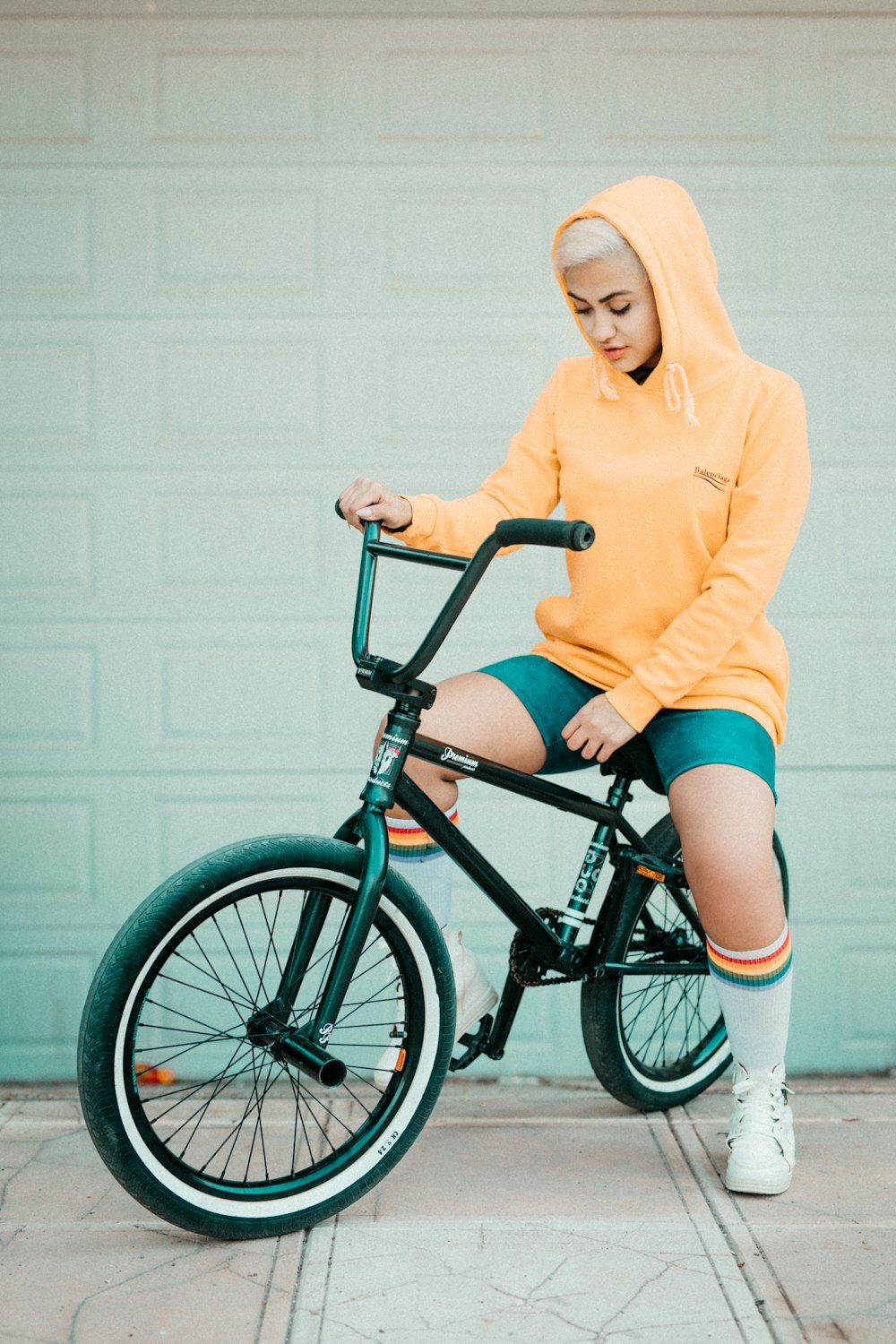 woman in yellow sweater riding black bmx bike