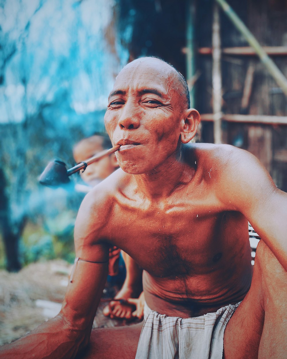 Hombre en topless fumando cigarrillo durante el día