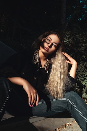 woman in black button up shirt and blue denim jeans sitting on green grass