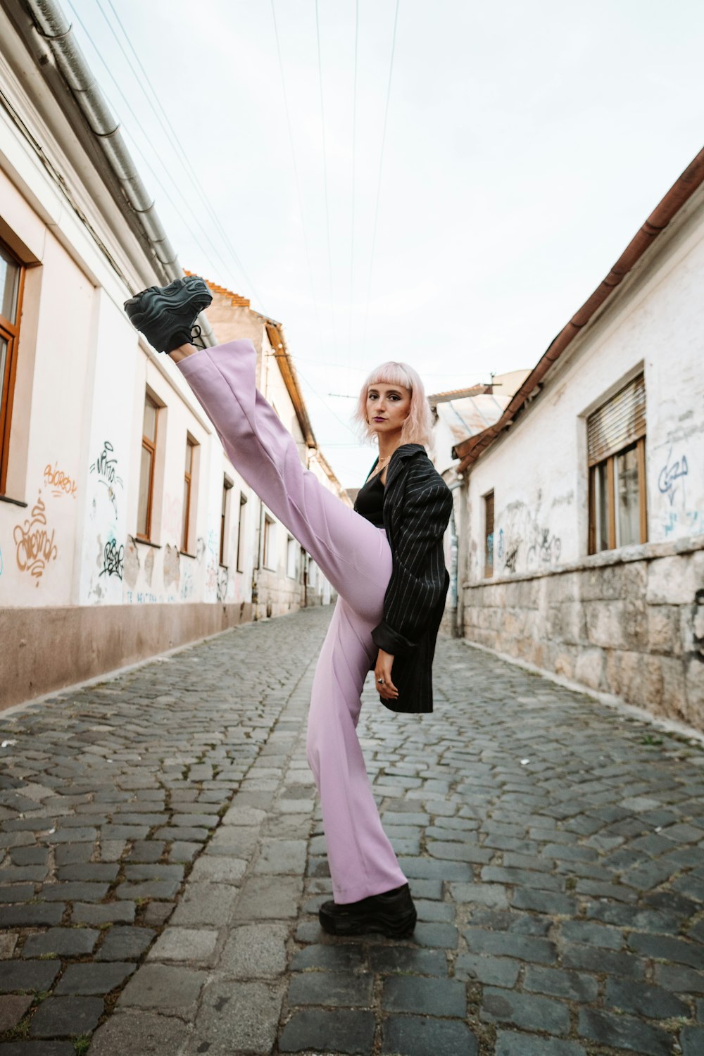 woman in black long sleeve shirt and pink pants holding her hair
