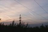High voltage power lines stretching across a clear sky at sunset.