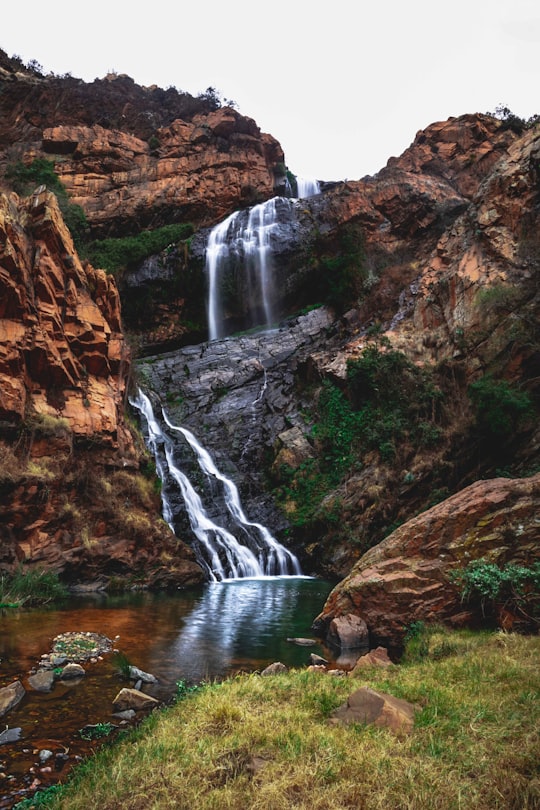 waterfalls between brown rocky mountain during daytime in Walter Sisulu National Botanical Garden South Africa