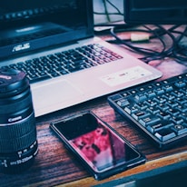 black smartphone beside black and silver laptop computer