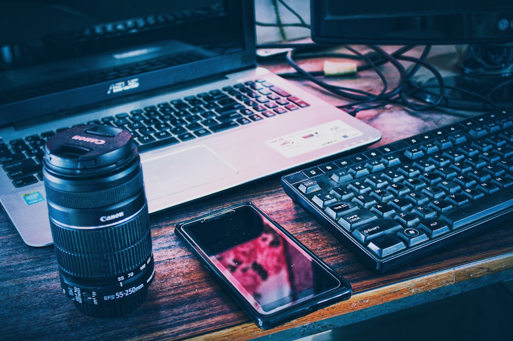 black smartphone beside black and silver laptop computer