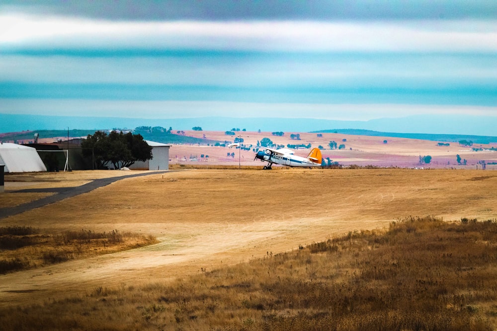 white and blue airplane on brown field during daytime