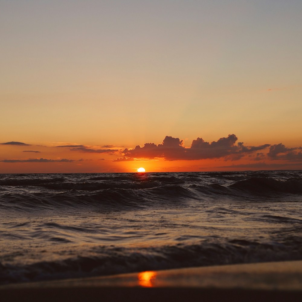 ocean waves crashing on shore during sunset