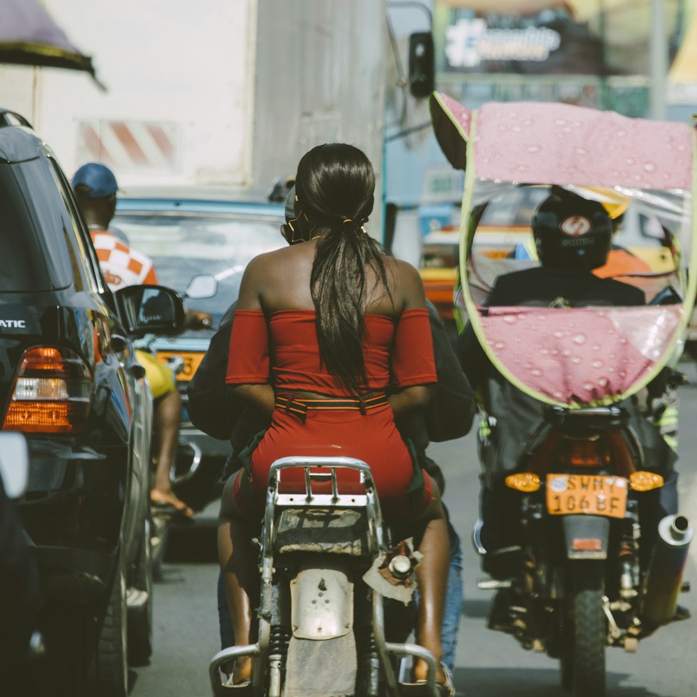 낮 동안 오토바이 옆에 서 있는 우산을 들고 빨간 민소매 드레스를 입은 여자