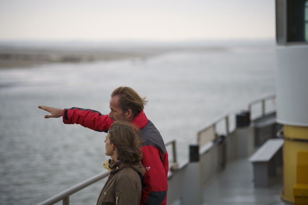 woman in red jacket and brown backpack standing on bridge during daytime