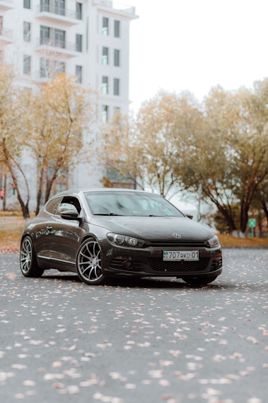 A sleek black taxi parked in front of a classic Parisian street with autumn leaves scattered around.
