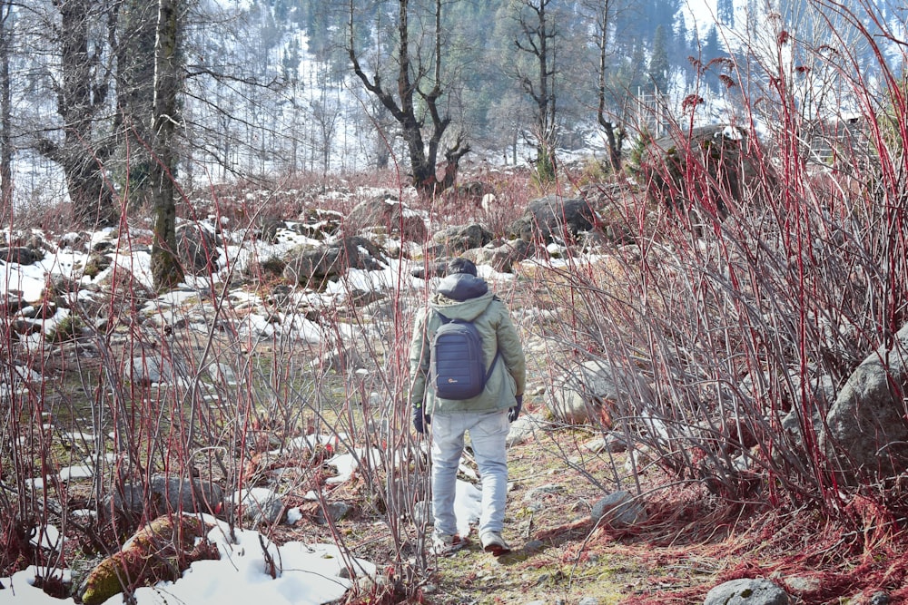 man in gray jacket and gray pants walking on snow covered ground during daytime