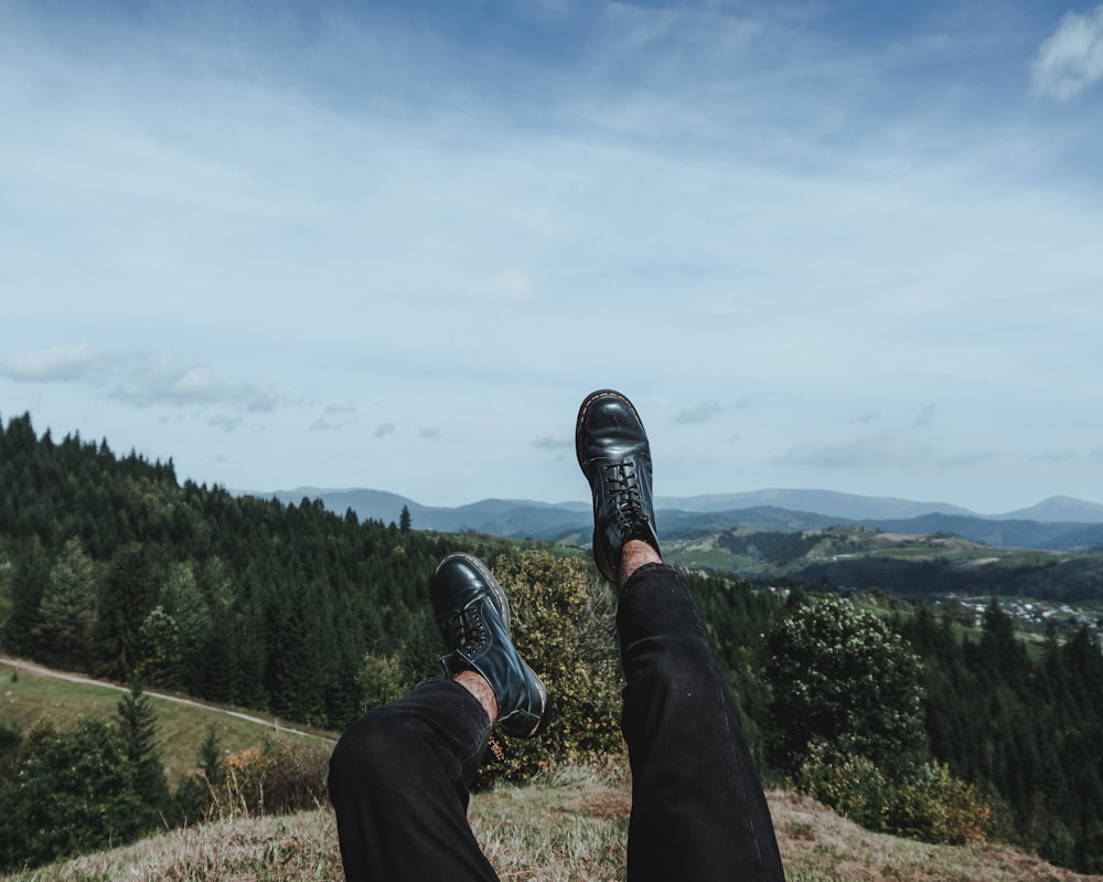 person in black pants and black shoes sitting on grass field during daytime