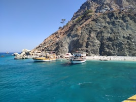 white boat on sea near brown rock formation during daytime