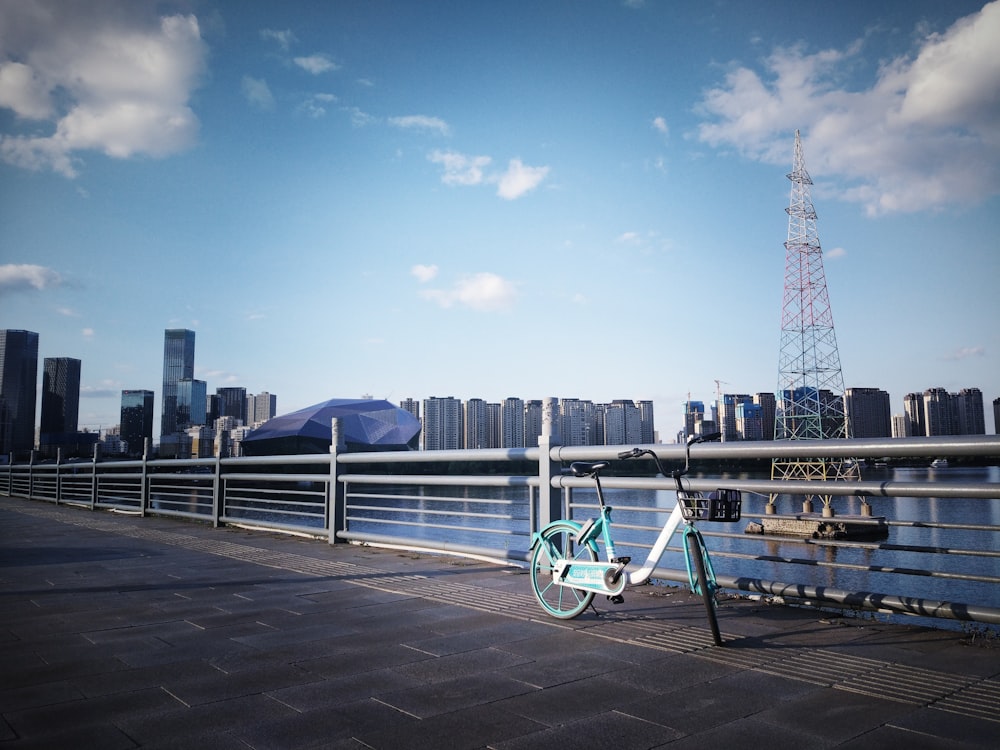 blue and white bicycle on gray metal railings near body of water during daytime