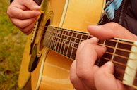 Close-up of skilled fingers picking a mandolin during an outdoor jam session.