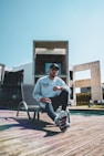 man in white crew neck t-shirt sitting on white metal chair during daytime