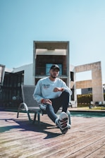 man in white crew neck t-shirt sitting on white metal chair during daytime