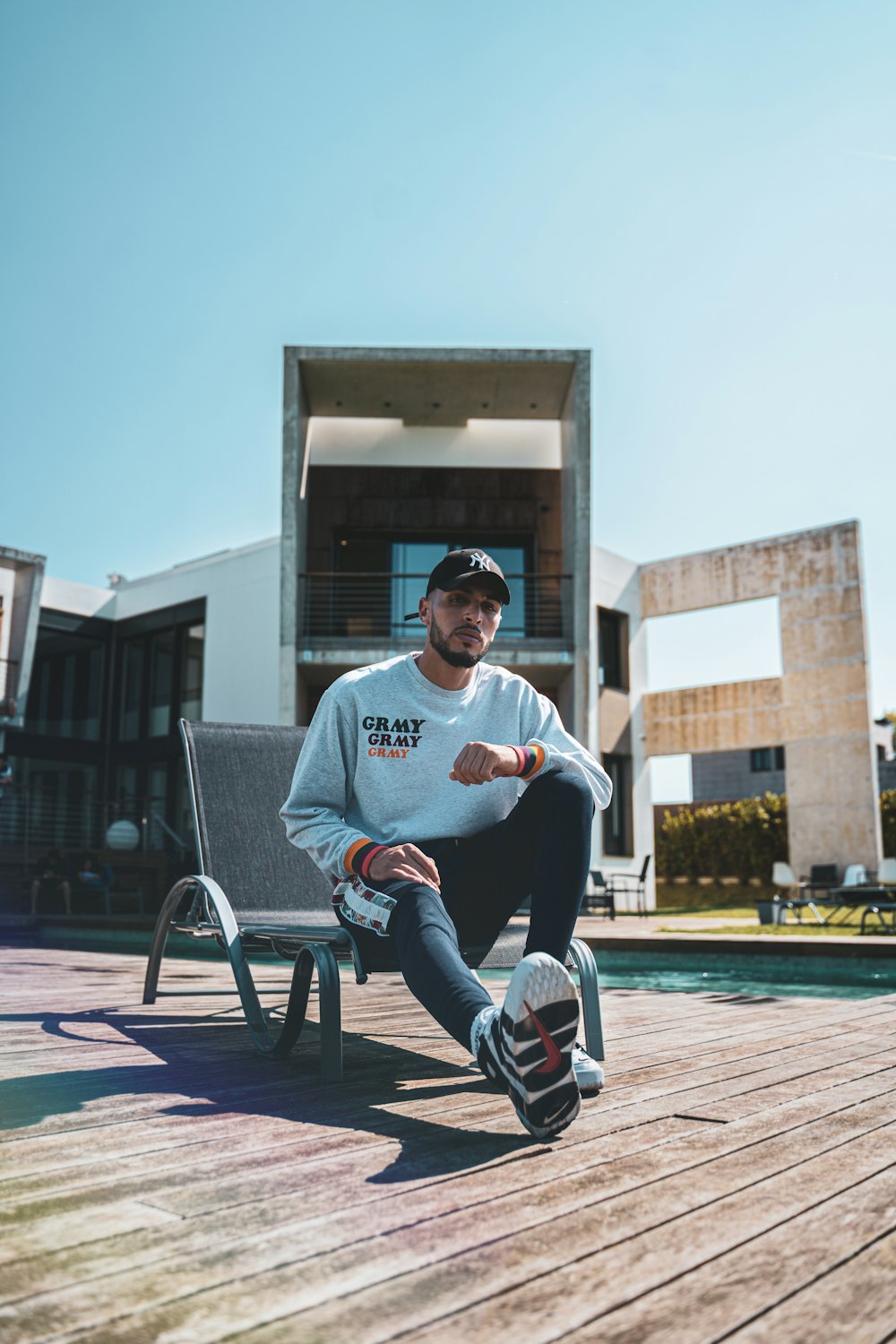 man in white crew neck t-shirt sitting on white metal chair during daytime