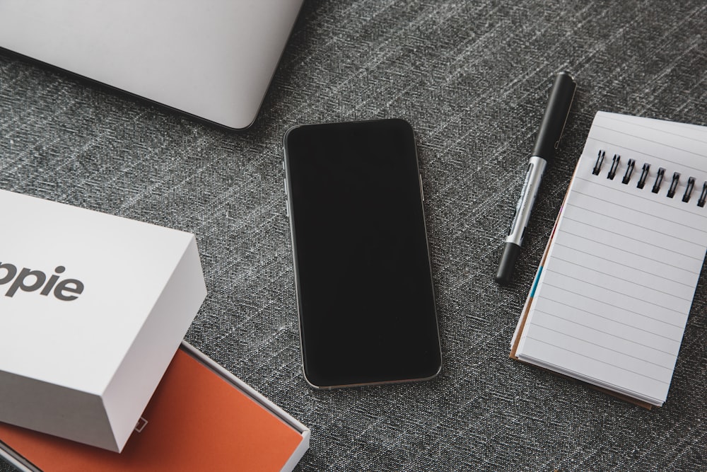 black ipad beside black pen