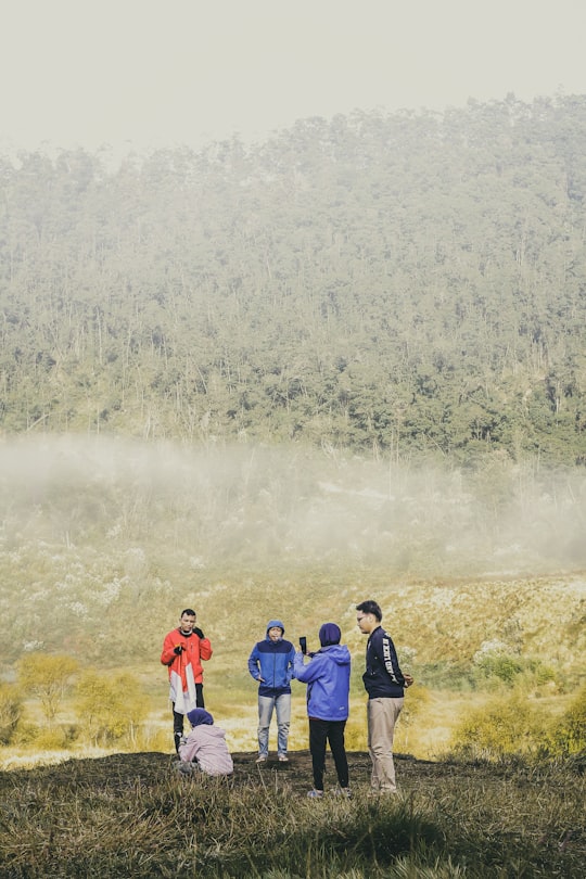 3 men and 2 women standing on green grass field during daytime in Dieng Indonesia
